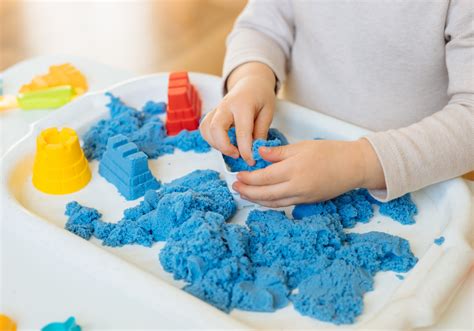 Een kind dat een zandmozaïek maakt met gekleurd zand