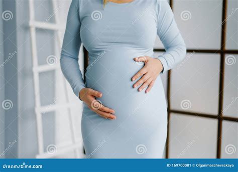 Een vrouw houdt haar buik vast, met op de achtergrond zachte, warme kleuren die een zwangerschapssfeer oproepen.