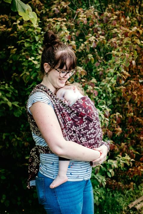 Een draagconsulent die een ouder helpt met het ergonomisch dragen van een baby in een draagdoek.