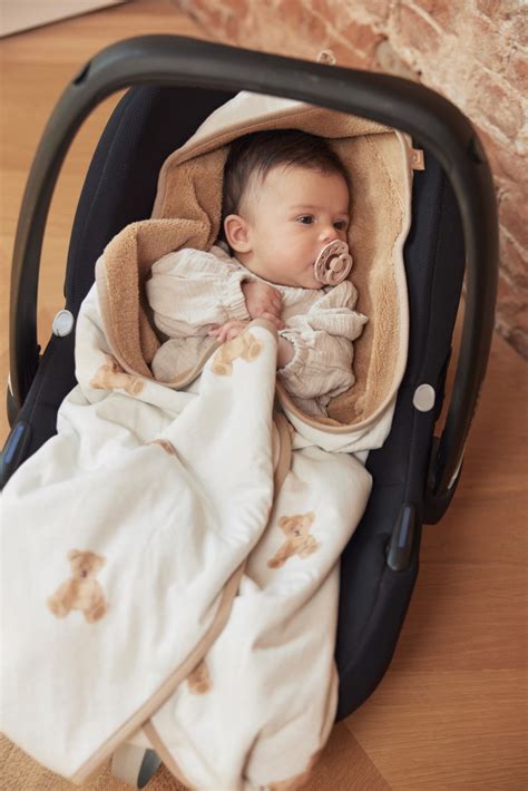 Baby in een Jollein wikkeldeken in een autostoeltje
