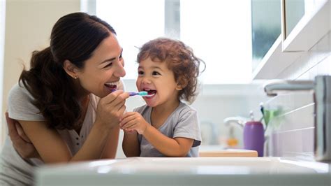 Een jong kind dat lachend probeert de tanden van zijn vader te poetsen