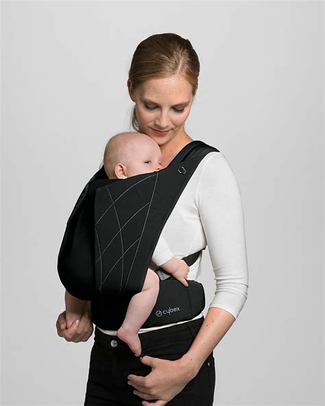 Een baby die comfortabel in de Cybex Yema Click draagzak wordt gedragen door een ouder, met focus op de ergonomische houding en het stijlvolle design van de draagzak.
