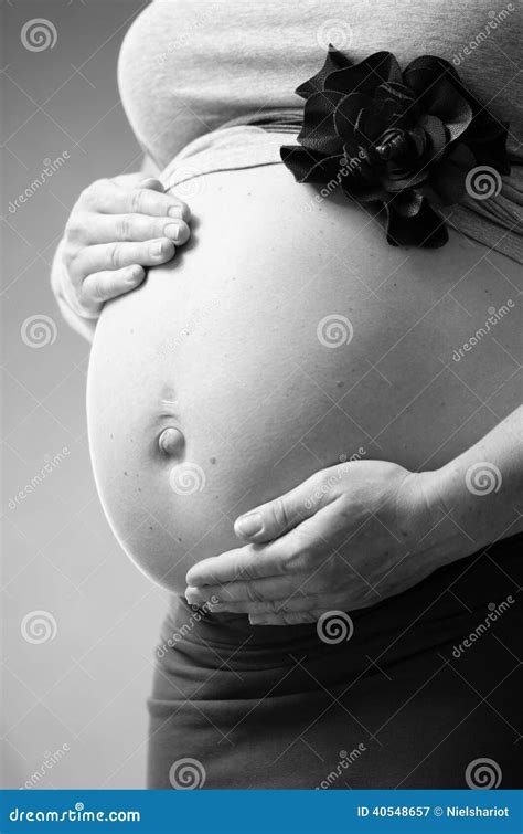 Vrouw met handen op haar zwangere buik, in profiel gefotografeerd