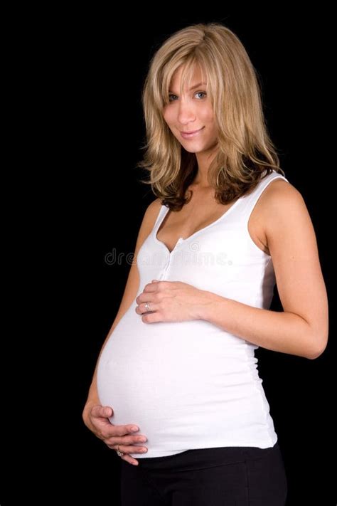 Vrouw in een witte blouse die openhangt langs haar zwangere buik