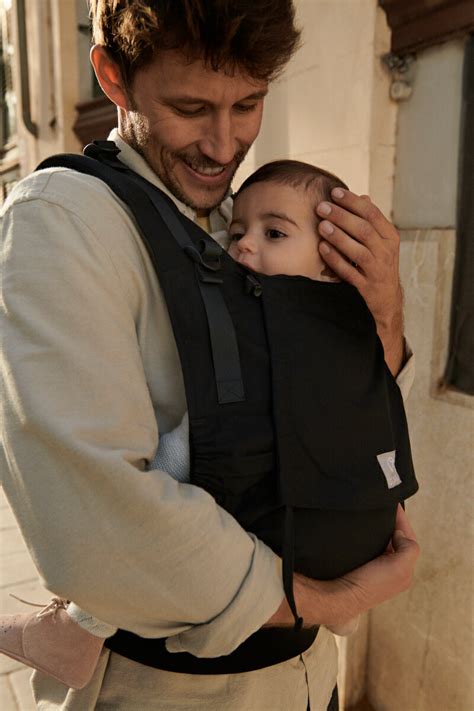 Afbeelding van een baby die comfortabel in een Stokke Limas draagzak wordt gedragen.