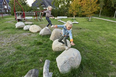 kinderen spelen in een natuurspeelplaats met diverse speelelementen