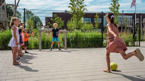 kinderen spelen op een schoolplein met een klimrek en waterpomp