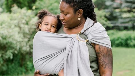 Een ouder die een baby in een hippe ringsling draagt.