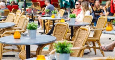 Vrouw in een luchtige zomerse zwangerschapsjurk op een zonnig terras