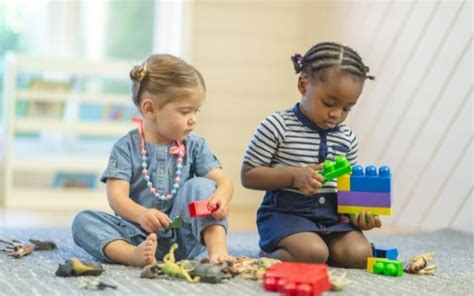 Twee peuters spelen samen in een verkleedhoek, met kostuums en accessoires.