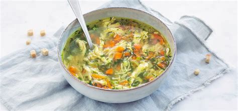 Een kom dampende kippensoep met groenten