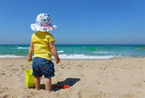 Een peuter die met een schepje en emmertje aan het spelen is bij een meer.