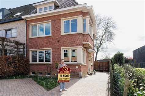 Foto van een stel dat lachend voor hun nieuwe huis staat met een 