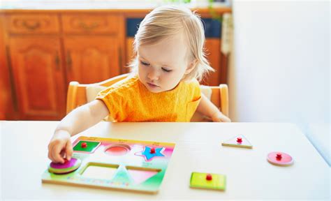 Een peuter die geconcentreerd naar een puzzel kijkt, met een paar stukjes al gelegd