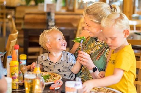 Verschillende gezinnen die genieten van een maaltijd in een restaurant met speelruimte voor kinderen