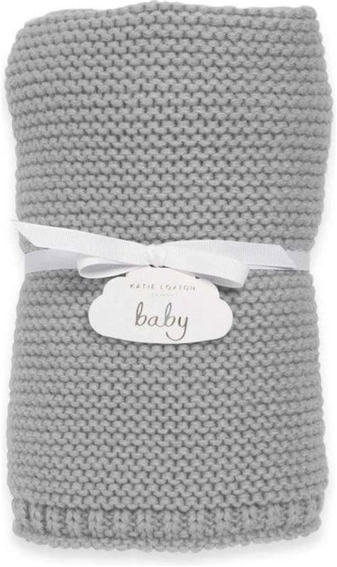 Een zacht, grijs gebreid dekentje dat opgevouwen ligt, met een focus op de textuur van het biologische katoen.