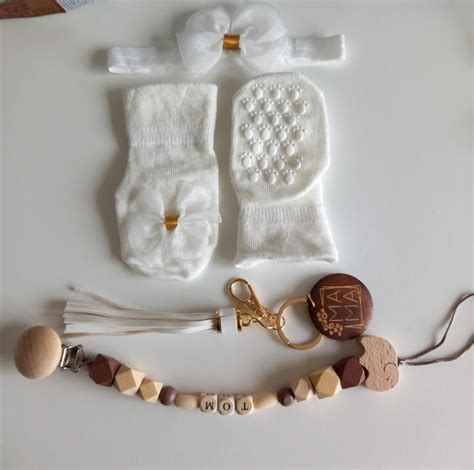 Een verzameling van babyverzorgingsproducten, waaronder een romper, mutsje, sokjes en een thermometer.