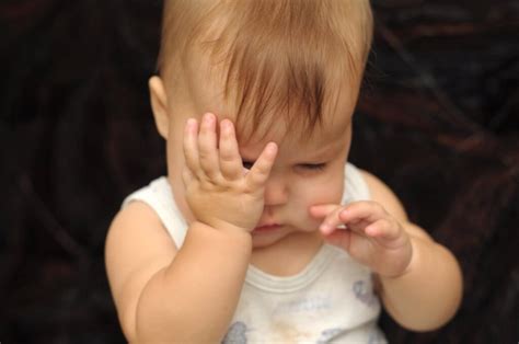 illustratie van een baby die in zijn ogen wrijft, met icoontjes die vermoeidheid, stof en allergenen aanduiden