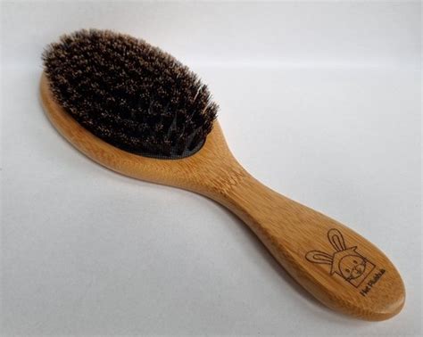 Konijn dat wordt geborsteld met een speciale borstel.