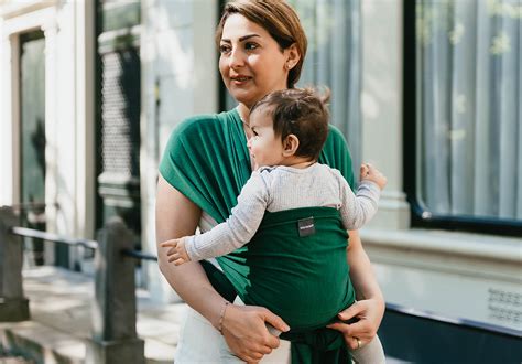 Een moeder die haar baby in een draagdoek vasthoudt, met een zachte glimlach.