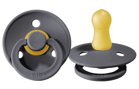 Een baby die een lichtgevende BIBS fopspeen vasthoudt in een donkere kamer