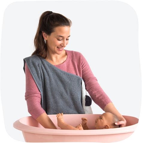 Illustratie van een baby die uit bad wordt gehaald met de Tuby badcape om de schouder van de ouder.