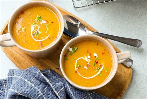 Foto van een kommetje met gepureerde pompoen en wortel, met een babylepel erin