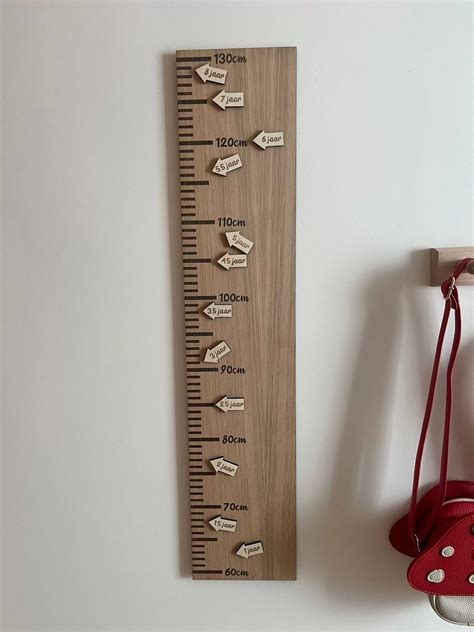 Een houten groeimeter met schaalverdeling en leuke illustraties.