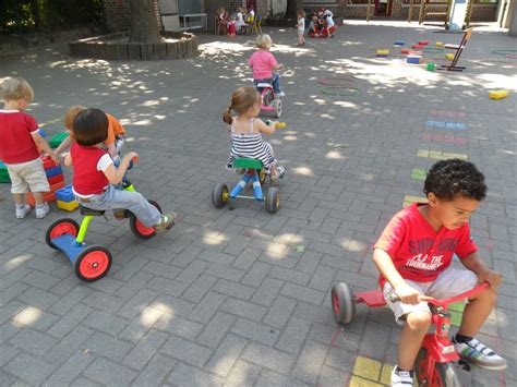 een groep peuters die vrolijk buiten spelen met diverse speelgoedartikelen