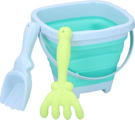 een vrolijk kind dat met een emmertje en schepje in een zandbak speelt