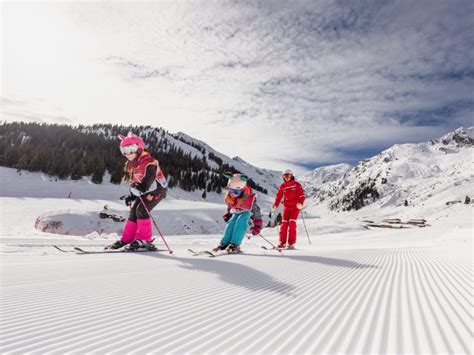kinderen leren skiën op een brede, glooiende piste