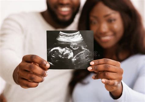 Een vrolijk stel kijkt naar een 3D echobeeld van hun baby.