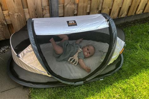Baby slaapt vredig in een reisbedje naast de camper