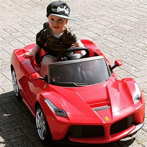 Kind dat lacht terwijl het rijdt in een rode elektrische Ferrari kinderauto