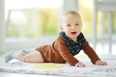 Baby die op zijn buik ligt op een kleurrijk speelkleed, hoofdje omhoog houdend