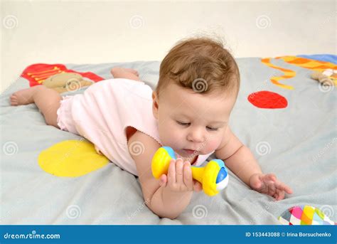 Baby die speelt met een spiegel en rammelaar tijdens tummy time op een zachte ondergrond