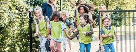 Foto van een groep kinderen die in het bos op zoek zijn naar sporen, passend bij het thema berenjacht.