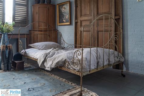 Een sfeervol ingerichte slaapkamer met een antiek Frans ijzeren bed.