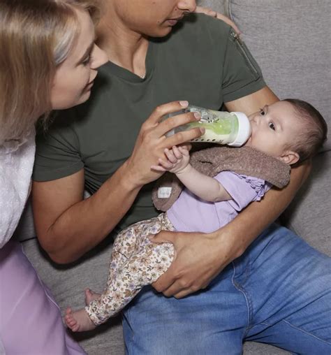 schematische weergave van de ideale houding voor het geven van flesvoeding, met baby half zittend en fles schuin gehouden