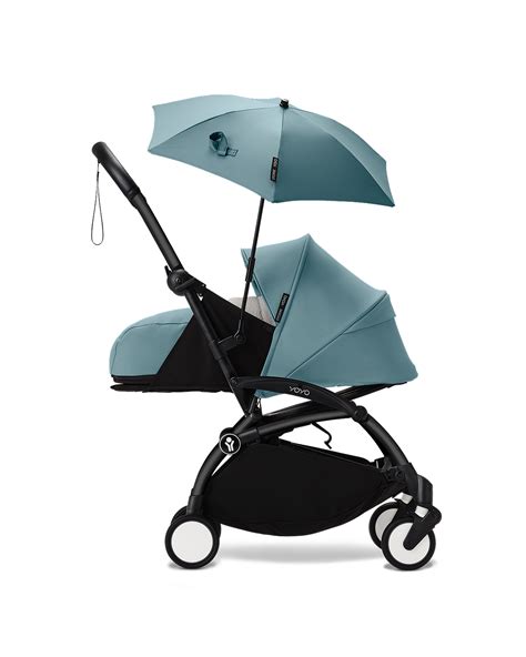 Foto van een kinderwagen met een bevestigde parasol die schaduw biedt aan de baby.