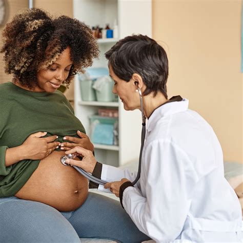 Een verloskundige luistert met een doptone naar het hartje van de baby.