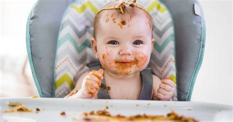 Baby van 12 maanden die aan tafel eet met het gezin