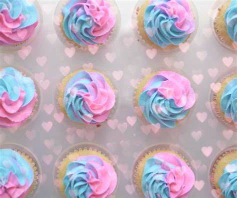 Decoratie en hapjes voor een gender reveal party: ballonnendozen, themacake, roze en blauwe cupcakes.