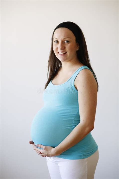 Een zwangere vrouw die haar buik vasthoudt met een serene uitdrukking