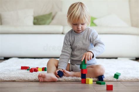 Een kind dat geconcentreerd speelt met houten blokken, bezig met het bouwen van een toren.
