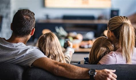 Een gezin dat gezellig samen films kijkt op de bank, met dekens en popcorn.