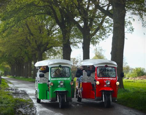 Groep mensen die in Tuktuks rijden door een dorp