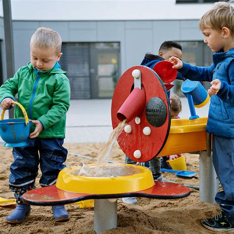 Kinderen die spelen met zand en water, met een bolderkar vol strandgereedschap.