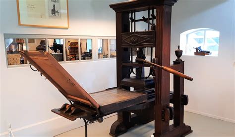 Historische foto van een drukkerij met antieke drukpers.