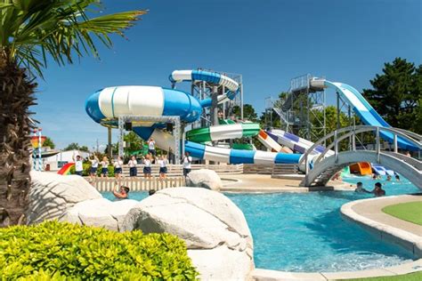 Een gezin met een peuter lacht in een zwembad met glijbanen op een camping in Zuid-Frankrijk